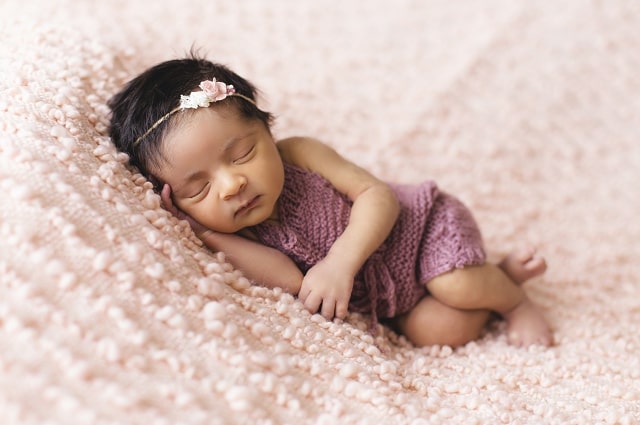 5 Ways to Help Keep Baby Safe While Sleeping, image of baby girl sleeping on soft pink sheets